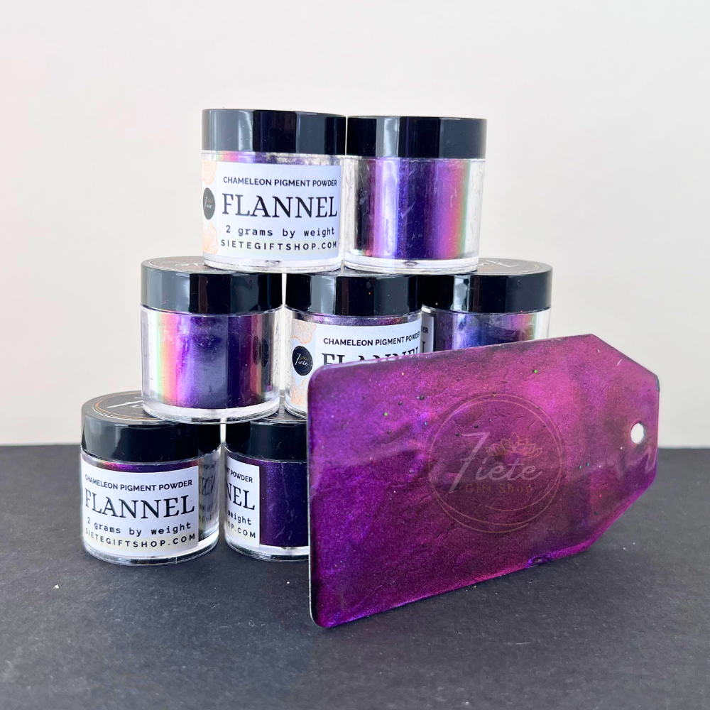 Chameleon pigment powder jars labeled “Flannel” arranged in a stack with a purple color-shift sample tag showcasing the rich violet and iridescent shimmer of the pigment.