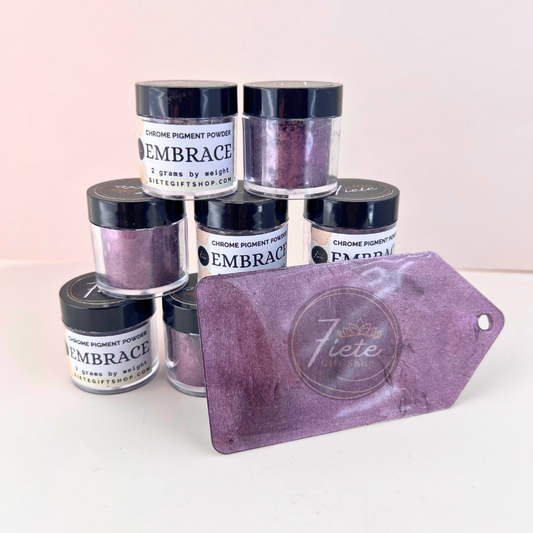 Embrace chrome pigment powder in a 2g jar from Siete Gift Shop, shown with a deep plum-purple metallic swatch and stacked pigment containers.