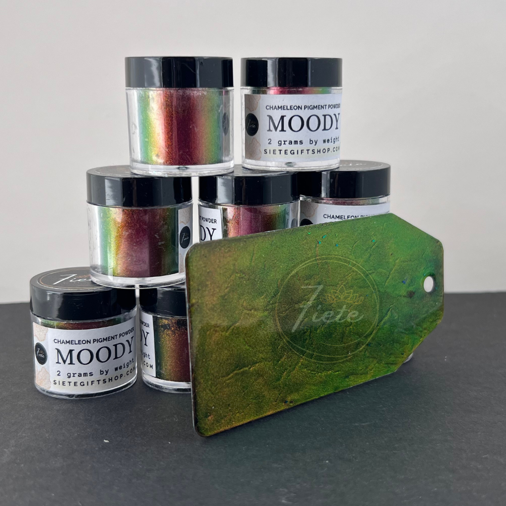 Chameleon pigment powder labeled “Moody” from Siete Gift Shop shown with multiple jars stacked and a green-to-gold color-shift sample tag displayed in front.