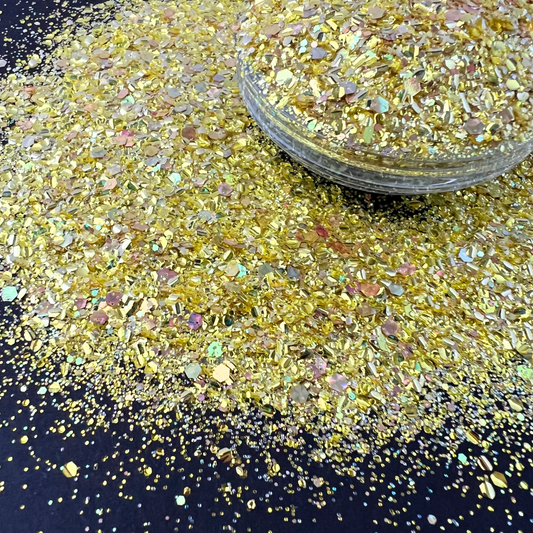 a vibrant custom glitter mix—predominantly yellow-gold with iridescent reflections and a variety of shapes and sizes, including hexagons, shards, and fine cuts.