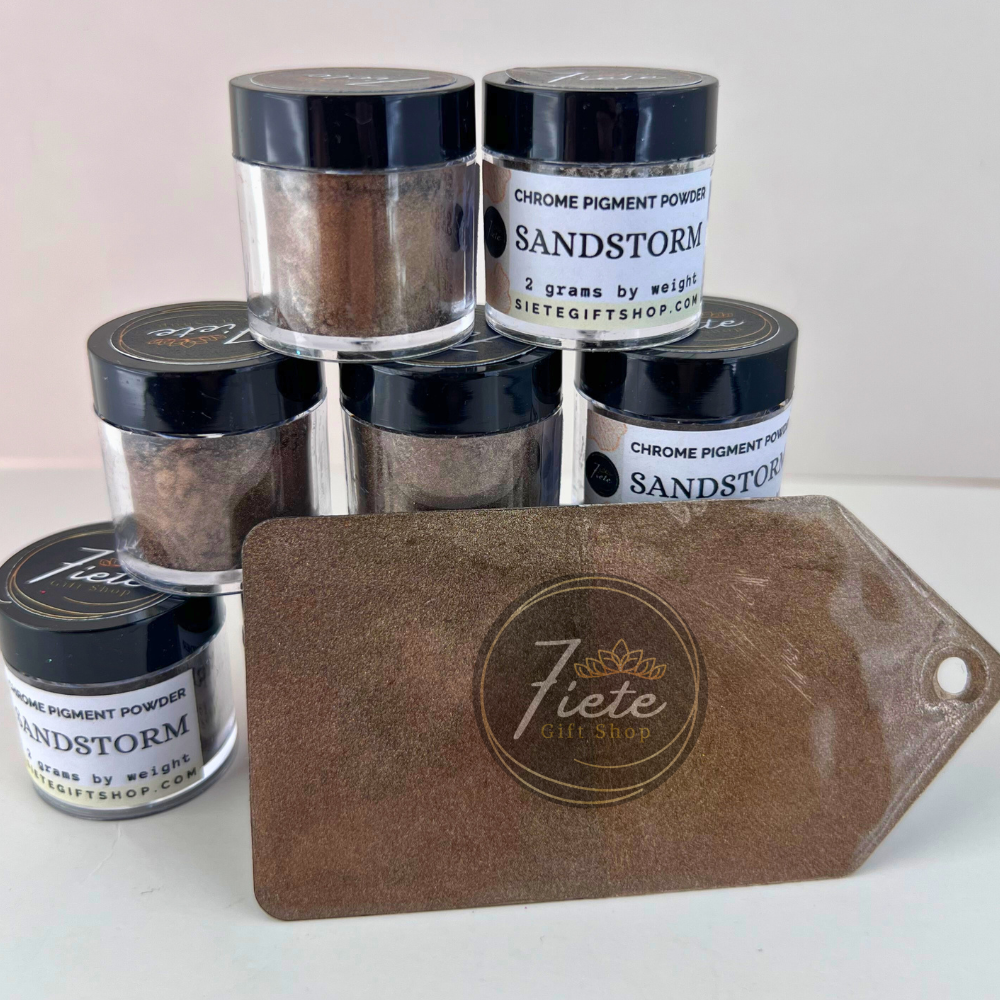 Jars of Sandstorm chrome pigment powder with a matching brown leather tag on a white background