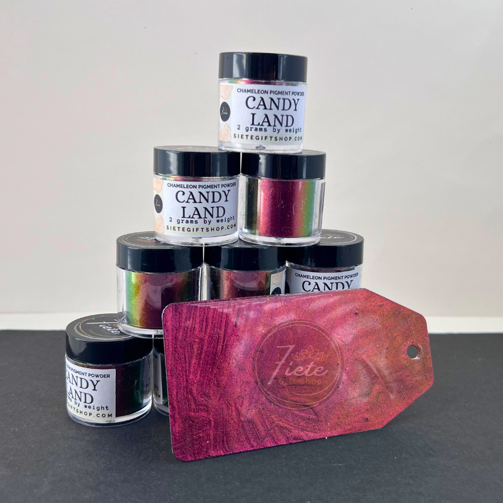 Stack of Siete Gift Shop ‘Candy Land’ chameleon pigment powder jars with a sample swatch tag showing a red-to-gold-to-green color shift.