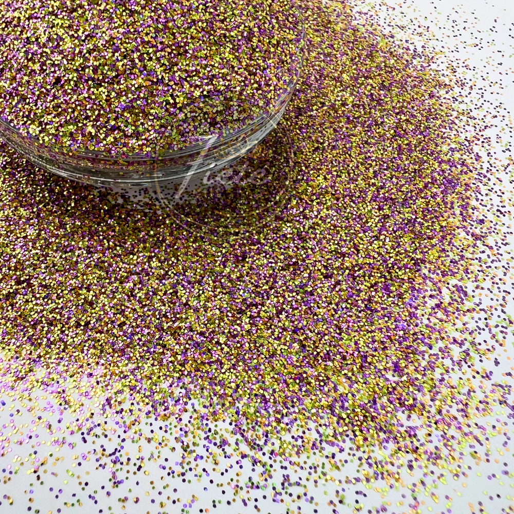 Close-up image of a custom glitter mix featuring shimmering purple, gold, and iridescent pieces scattered around a clear container, showcasing its high sparkle and colorful blend.