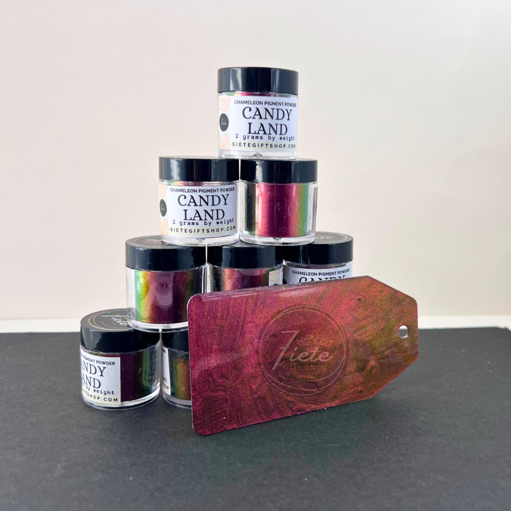 Stack of Siete Gift Shop ‘Candy Land’ chameleon pigment powder jars with a sample swatch tag showing a red-to-gold-to-green color shift.