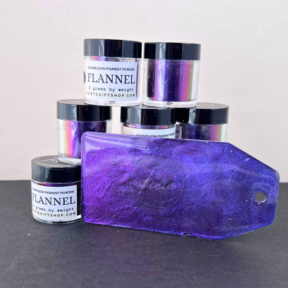 Chameleon pigment powder jars labeled “Flannel” arranged in a stack with a purple color-shift sample tag showcasing the rich violet and iridescent shimmer of the pigment.