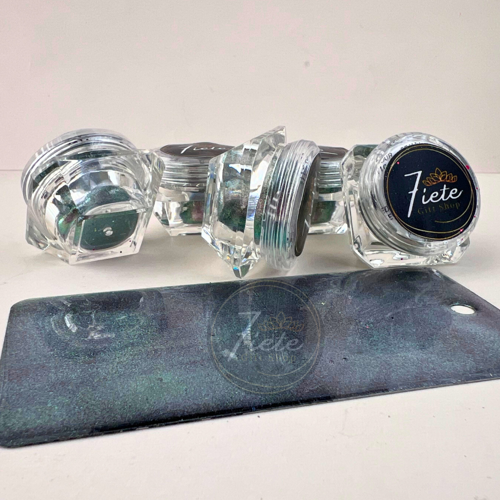 Stacked jars of Georgette chameleon pastel pigment powder from Siete Gift Shop with a green and teal color-shifting sample swatch in front.