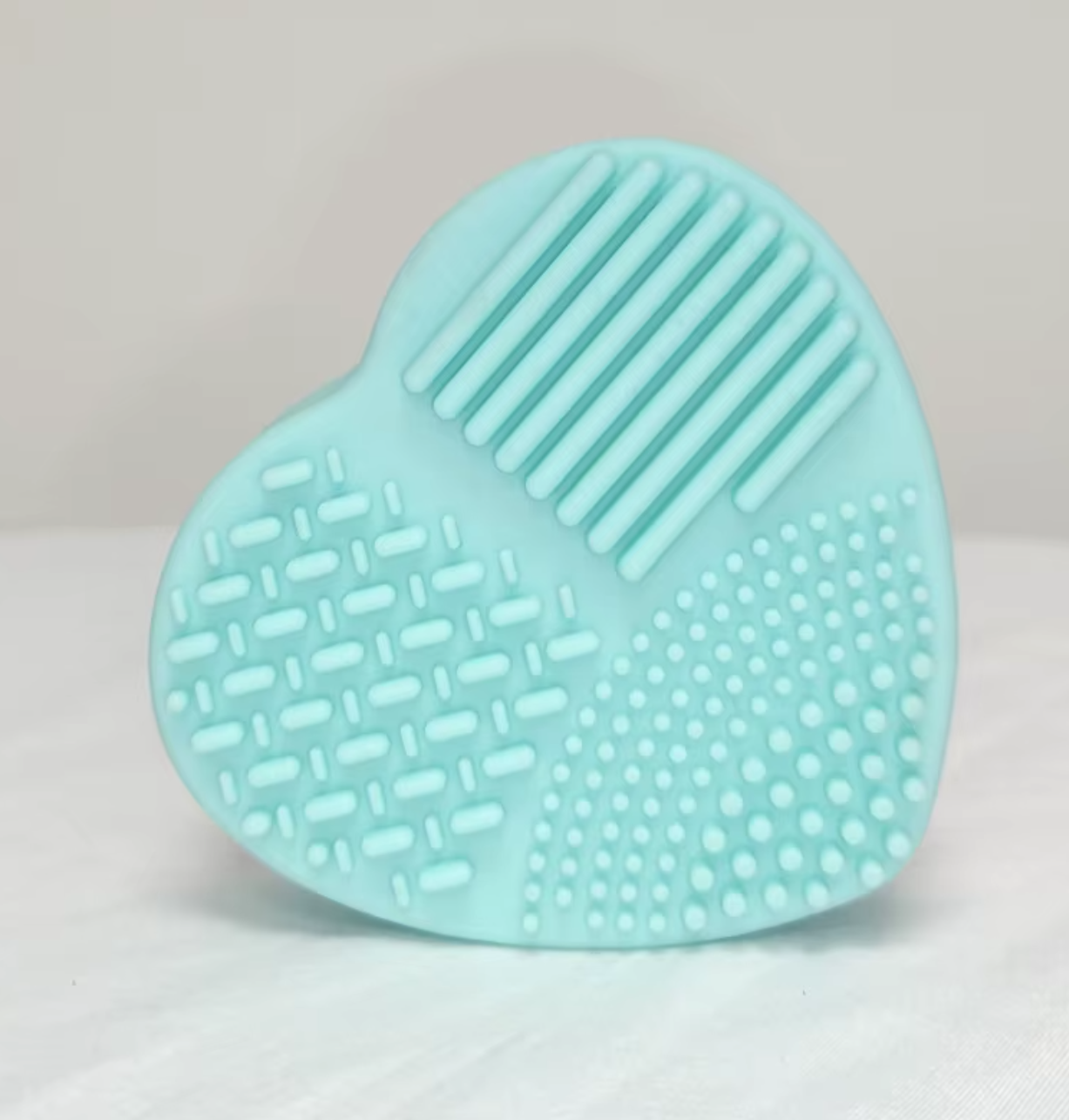 Brush Buddy heart-shaped silicone brush cleaning tool with textured scrubber and sponge insert, used to clean glitter and pigment brushes for crafting and tumbler making.