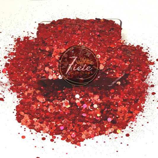 Red holographic chunky mix glitter over spilling from short clear container. The glitter is picking up different shades of reds, some subtle pinks and oranges.